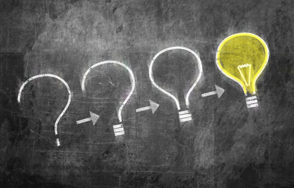 A chalkboard with the drawing of a question mark progressing into a light bulb.
