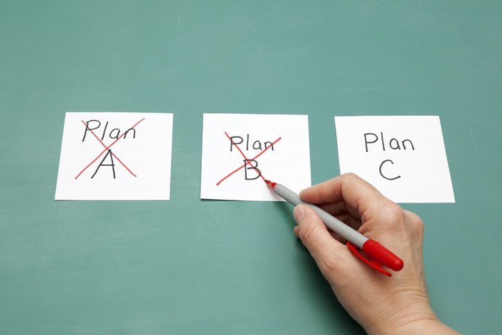 Three sticky notes next to each other on a board. One says "Plan A", the next says "Plan B", the last says "Plan C". Plan A and Plan B each have a red X on them.