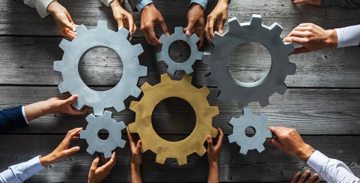 A set of gears with each gear held by a pair of human hands
