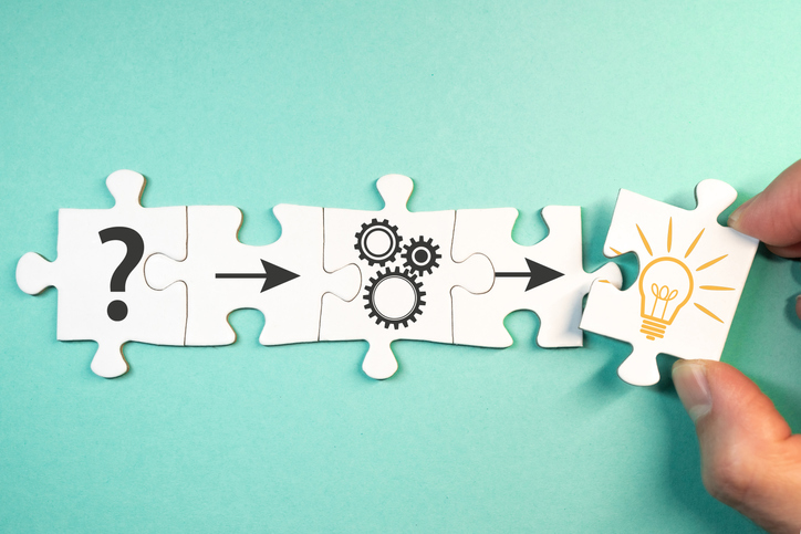 Five puzzle pieces being placed together, each with an illustration on them. From left to right: A question mark, an arrow pointing to the right, a set of three round gears, an arrow pointing right, a light bulb